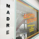 西公園のアメリカ料理店MADRE マドレの外観です。MADREとかかれたお店の看板の横のお店の窓にはAMERICAN LOCAL FOODとかかれています